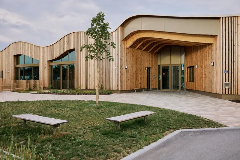 Kita Unterm Regenbogen: geschwungene Holz-Aluminium-Fassade mit gebogenen Riegeln