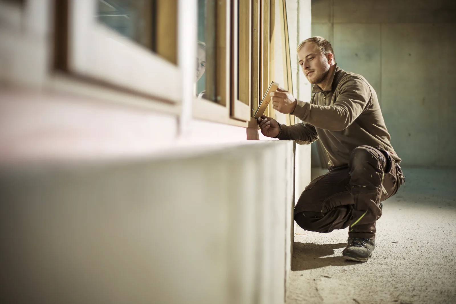 Konzentrierte Feinarbeit am Holz-Alu-Fenster auf der Baustelle