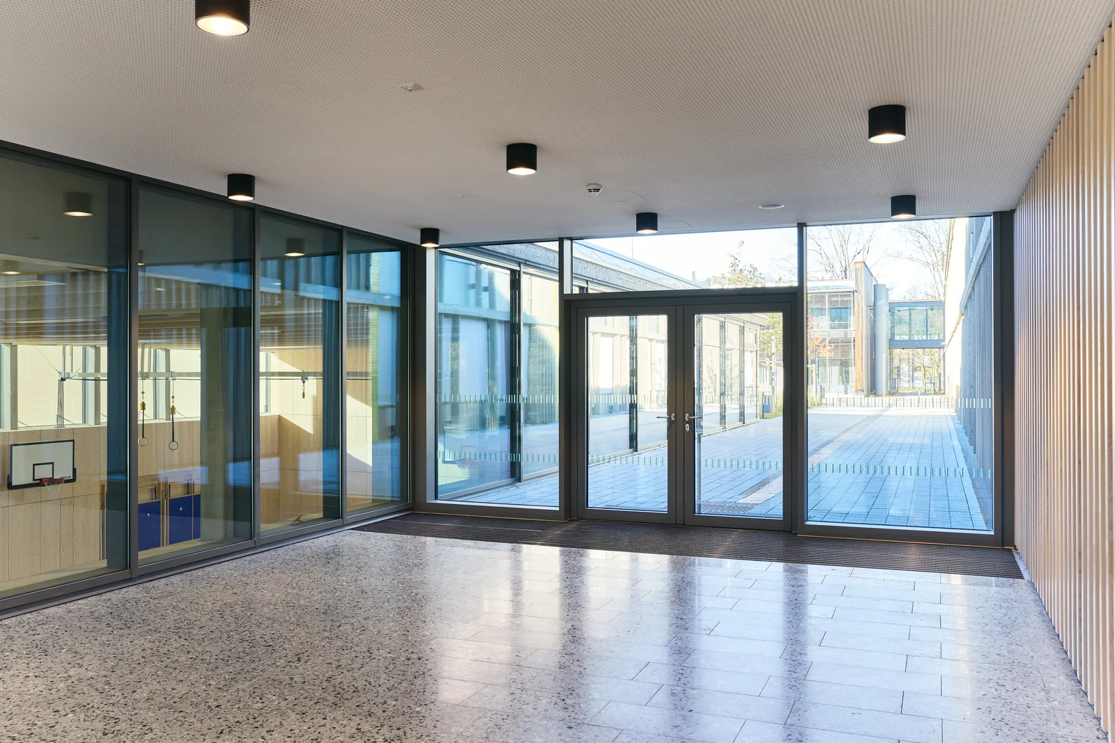 Blick durch die Holz-Aluminium-Fassade der FOS/BOS Rosenheim auf den Pausenhof