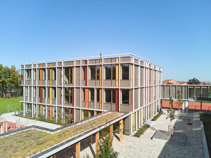 Grund- und Mittelschule Landau an der Isar: Holz-Alu-Pfosten-Riegel-Fassade mit senkrechten Lisenen und farbigen Feldern, Pausenhofseite