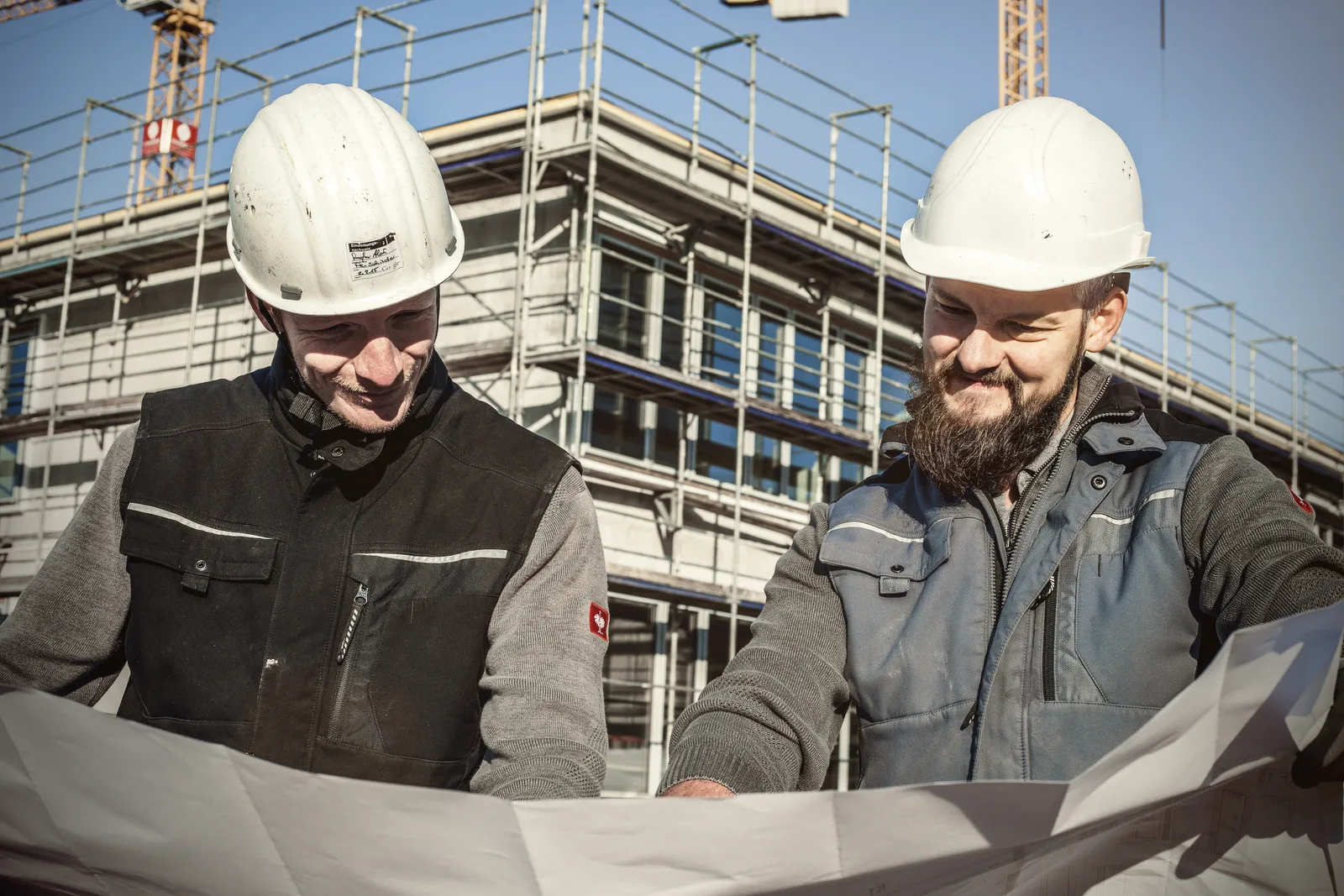 Zwei Heigl-Monteure prüfen den Werkplan vor dem eingerüsteten Rohbau